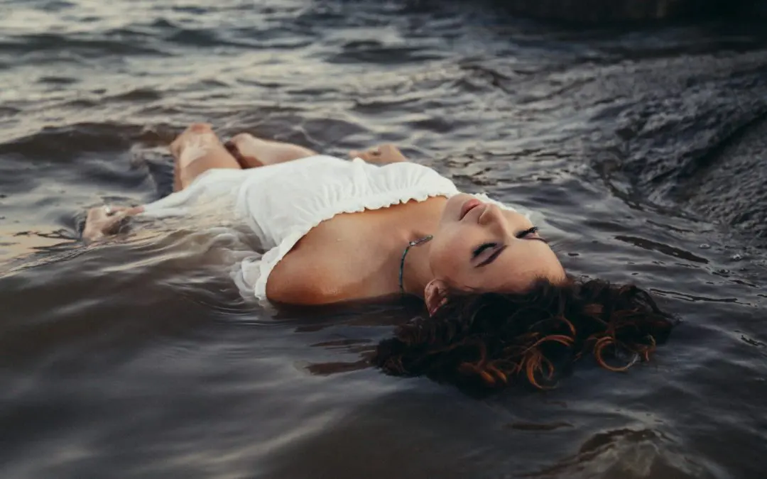 Woman in white dress floating in water