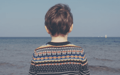 Person in patterned sweater facing the sea.