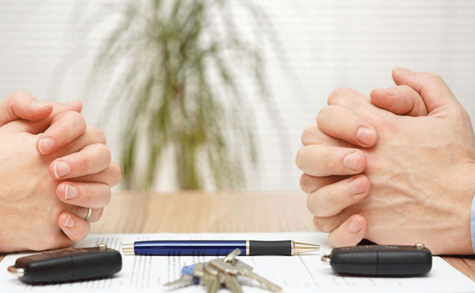 Hands clasped over car keys and contract