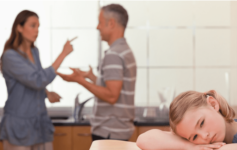Upset girl leaning on table amid parental argument