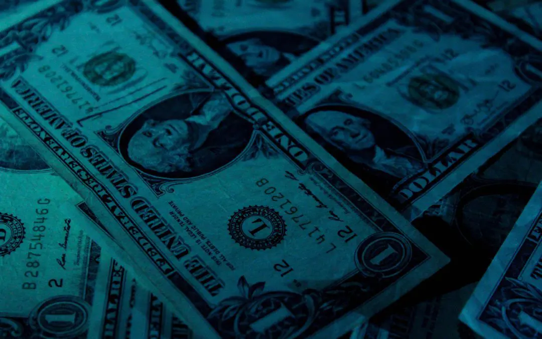 Close-up of US one-dollar bills under teal light