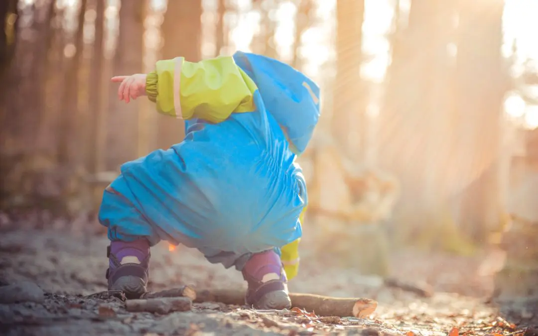 Toddler in blue snowsuit crouching outdoors