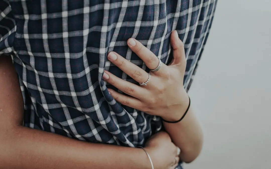 Hands clasped around person wearing plaid shirt