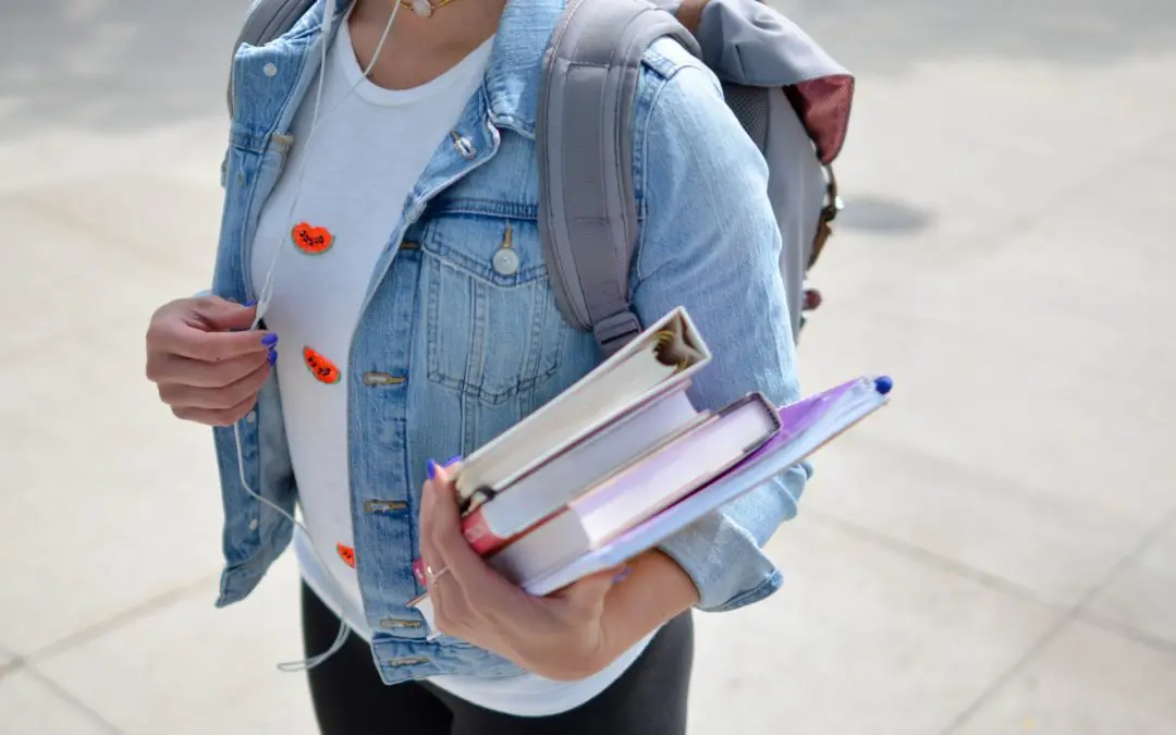 Student holding books and wearing backpack