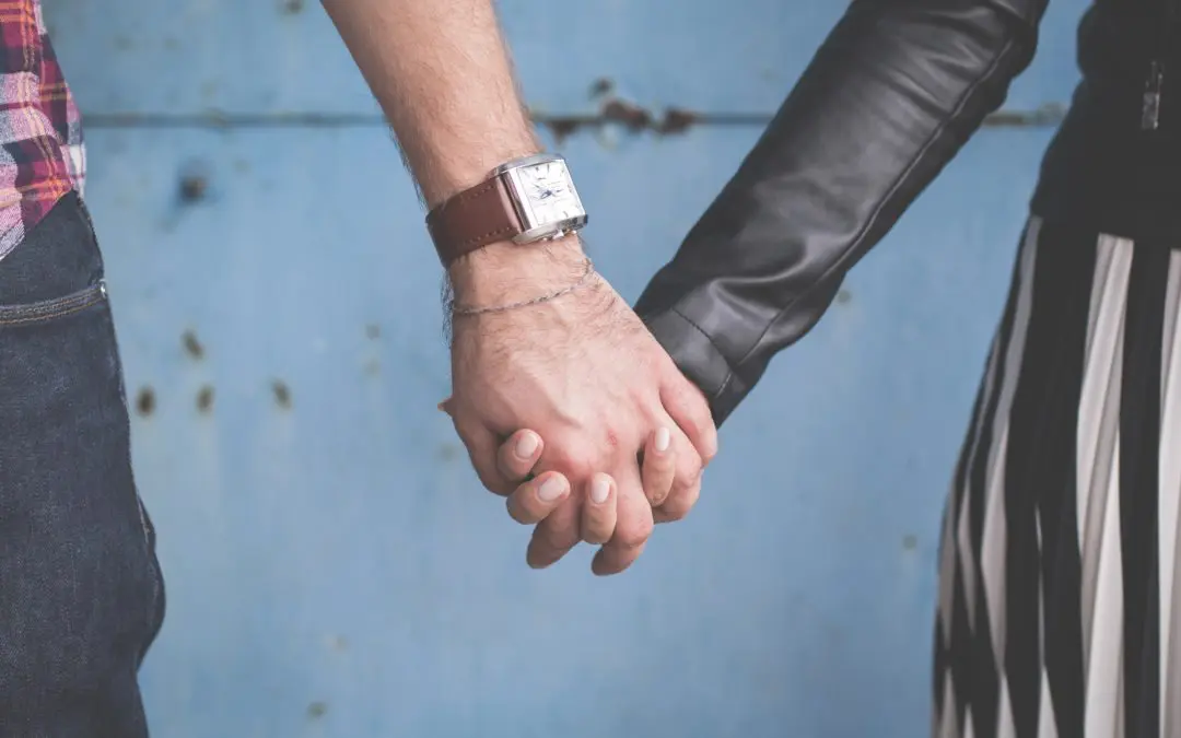 Two people holding hands against a blue wall