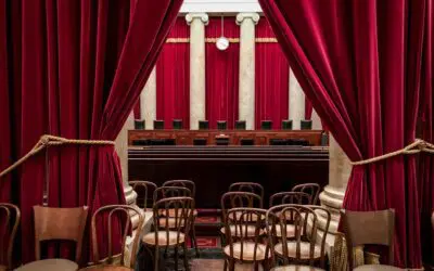 Red-curtained courtroom with empty wooden chairs