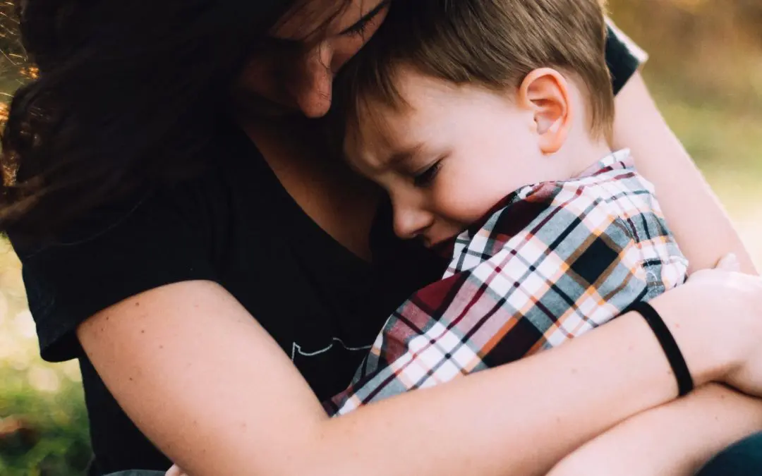 Adult embracing distressed young child
