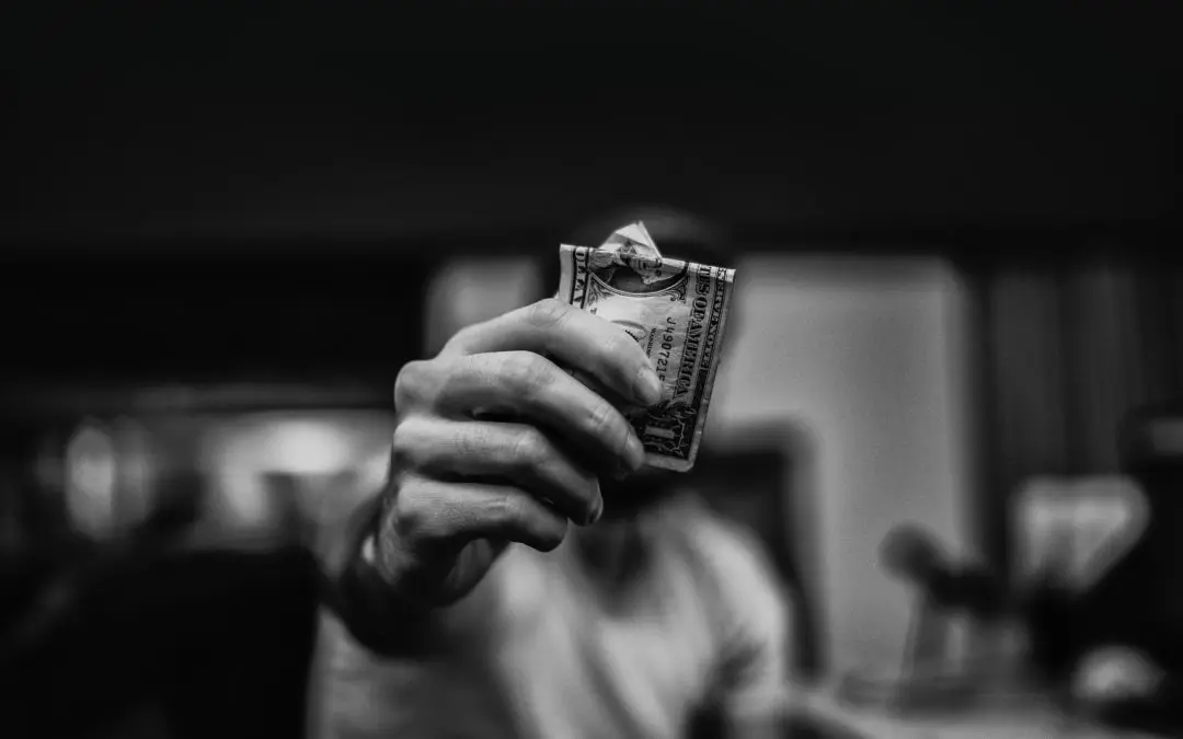 Hand holding crumpled dollar bill
