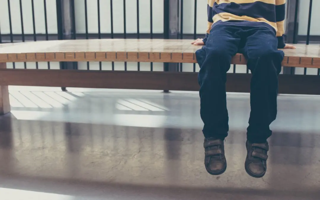 Child sitting on bench, legs dangling