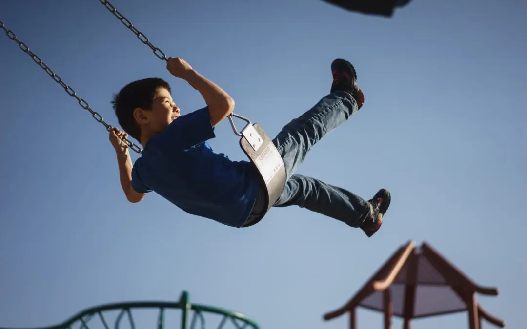 Child on swing against clear blue sky