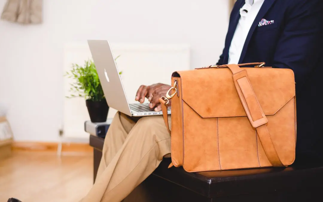 Leather briefcase beside person using laptop