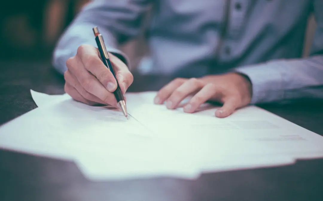 Person signing documents with a pen