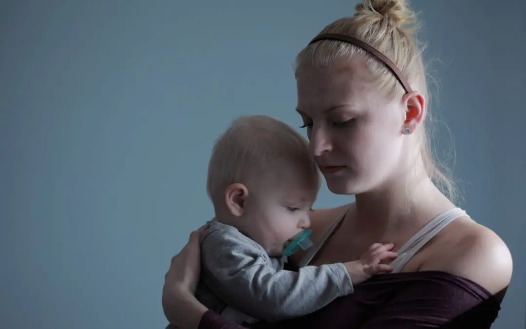Young mother holding baby with pacifier