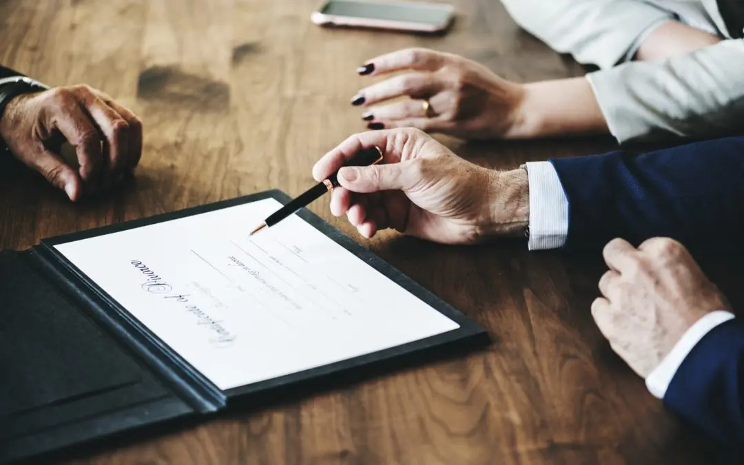 Hands pointing to contract on wooden table