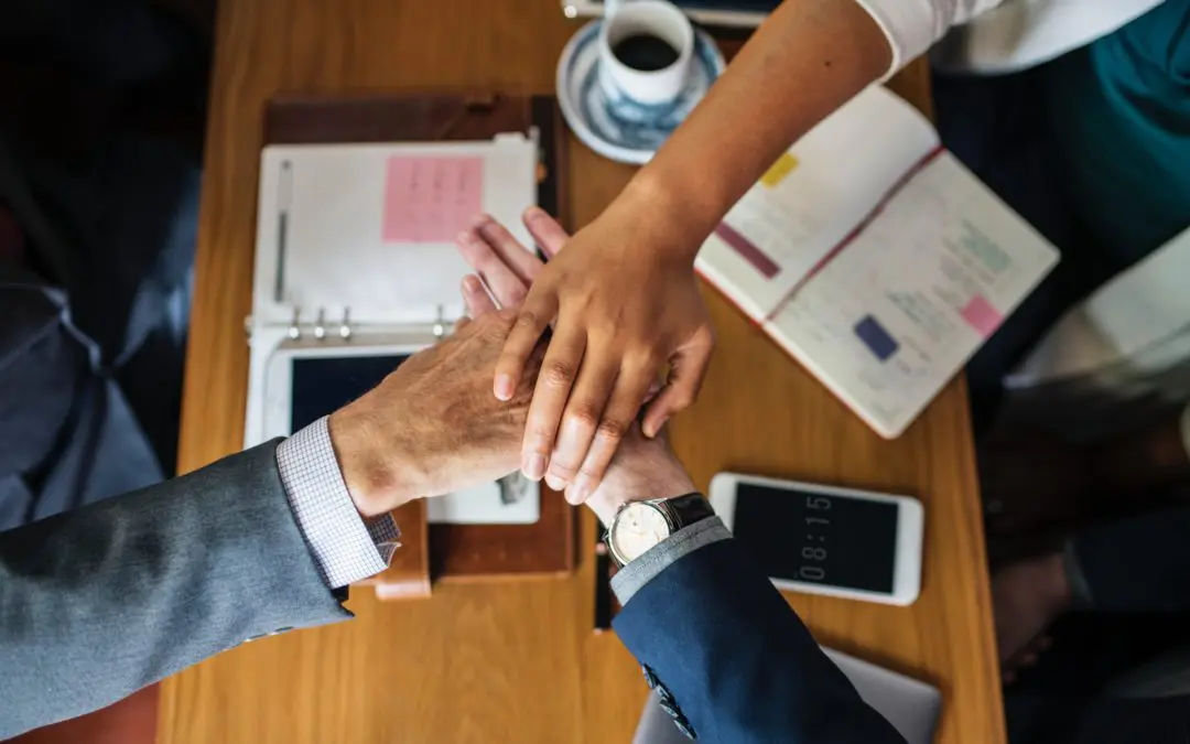 Hands stacked in teamwork over desk