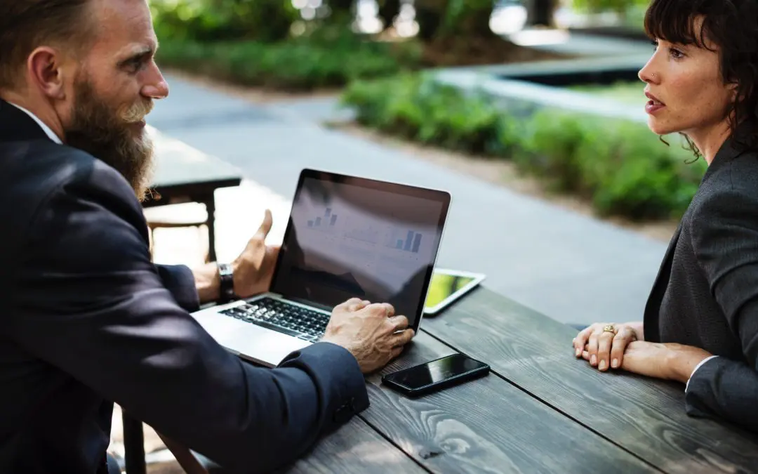 Two professionals discussing laptop outdoors
