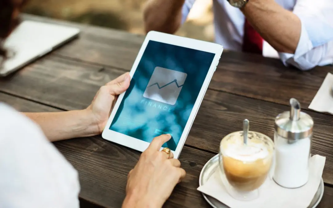 Hands holding tablet displaying finance app, coffee