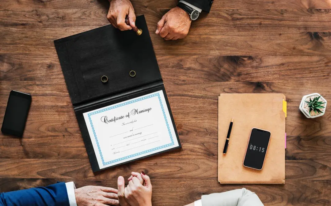 Couple holding hands over marriage certificate