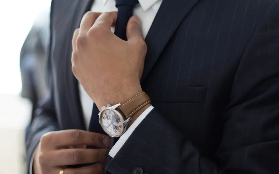 Person adjusting tie with watch and suit