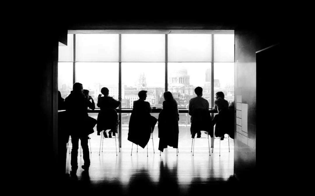 Silhouettes of people seated by large window