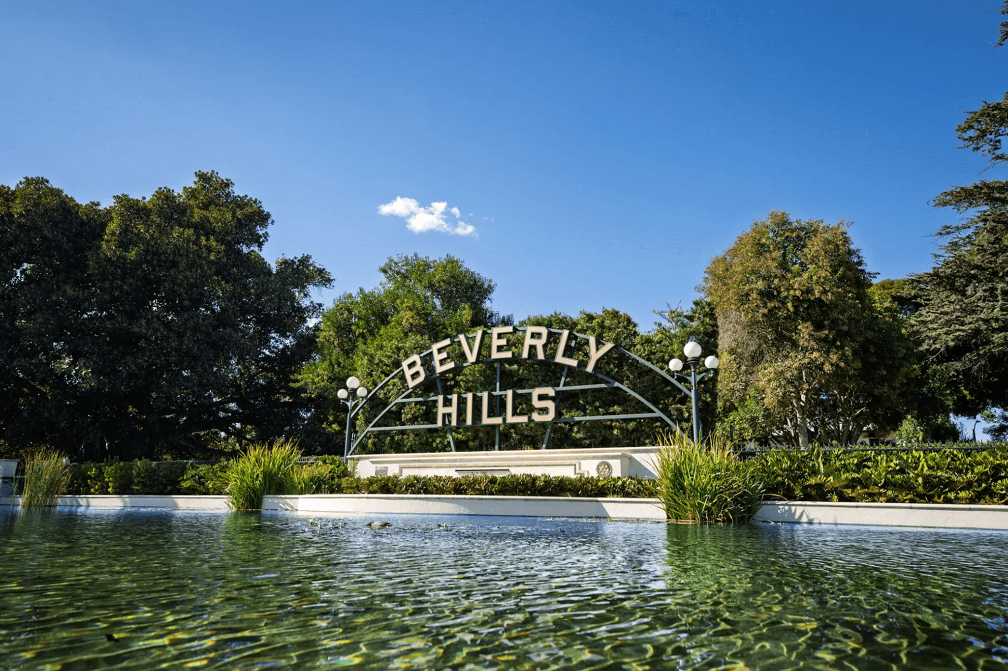Beverly Hills sign with trees and water.