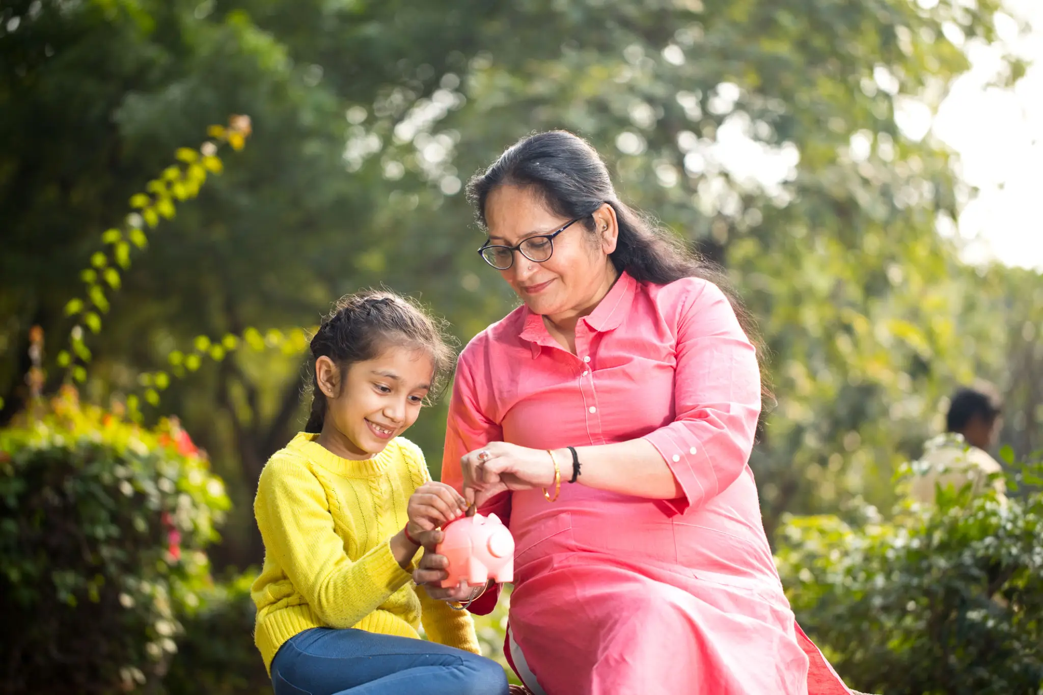 Grandmother and granddaughter with piggy bank.