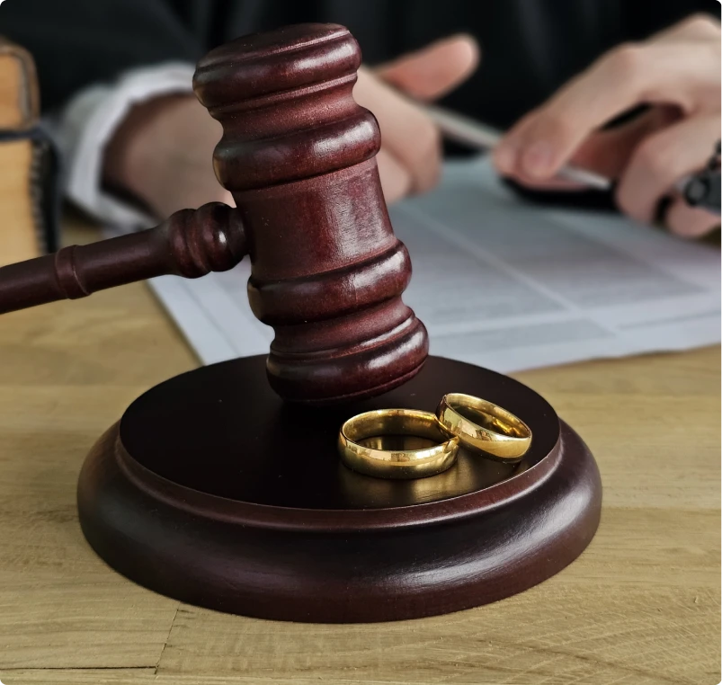 Gavel with wedding rings on wooden table.