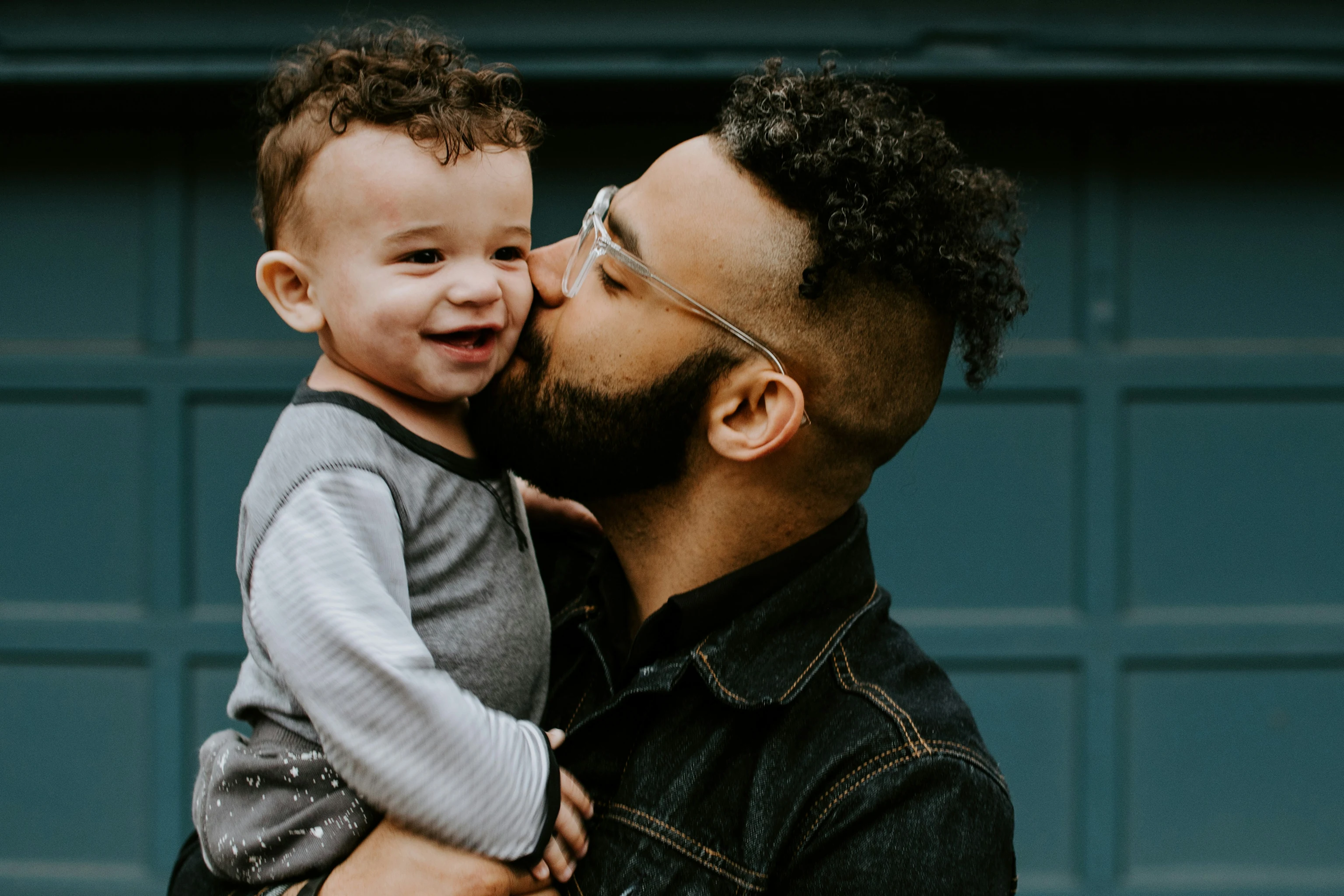 Father kissing smiling toddler's cheek
